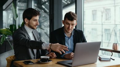 Two businessmen pointing laptop screen while discussing
